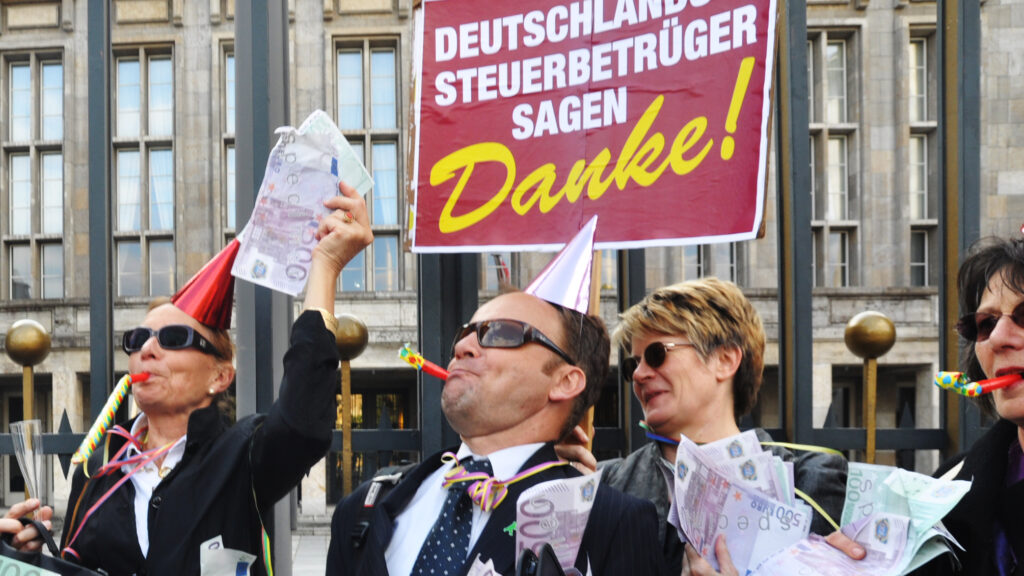 Da jubeln die Straftäter im Anzug: Als 2011 das Steuerabkommen mit der Schweiz formuliert wird, stellen wir uns vor das Finanzministerium und mimen die, die davon profitieren. Menschen, die uns um unser Steuergeld betrügen. Denn die sollten straffrei davonkommen.