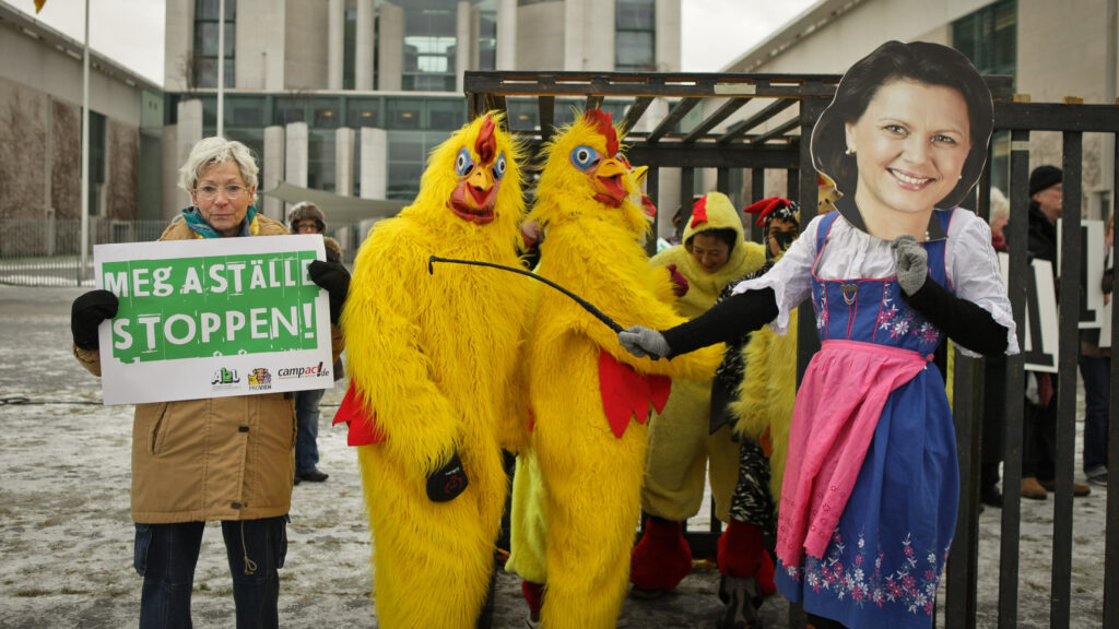 Hühnertanz vorm Kanzleramt. So protestierte Campact gegen Massentierhaltung und für mehr Bürgerbeteiligung beim Bau von Mastanlagen. Eine Frau im Ilse-Aigner-Kostüm wollte die Tiere zurück in den Käfig jagen, blieb aber ohne Erfolg.