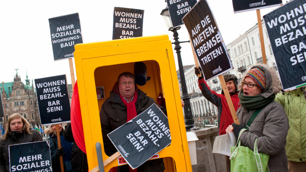 Olaf Scholz im Visier unserer Miet-Aktion – 2013 als Hamburgs Bürgermeister. Denn Wohnungen wurden zu dieser Zeit für Normalverdienende immer teurer. Um ihn mit dieser Not zu konfrontieren, boten wir auf dem Jungfernstieg eine Telefonzelle zur Miete an.