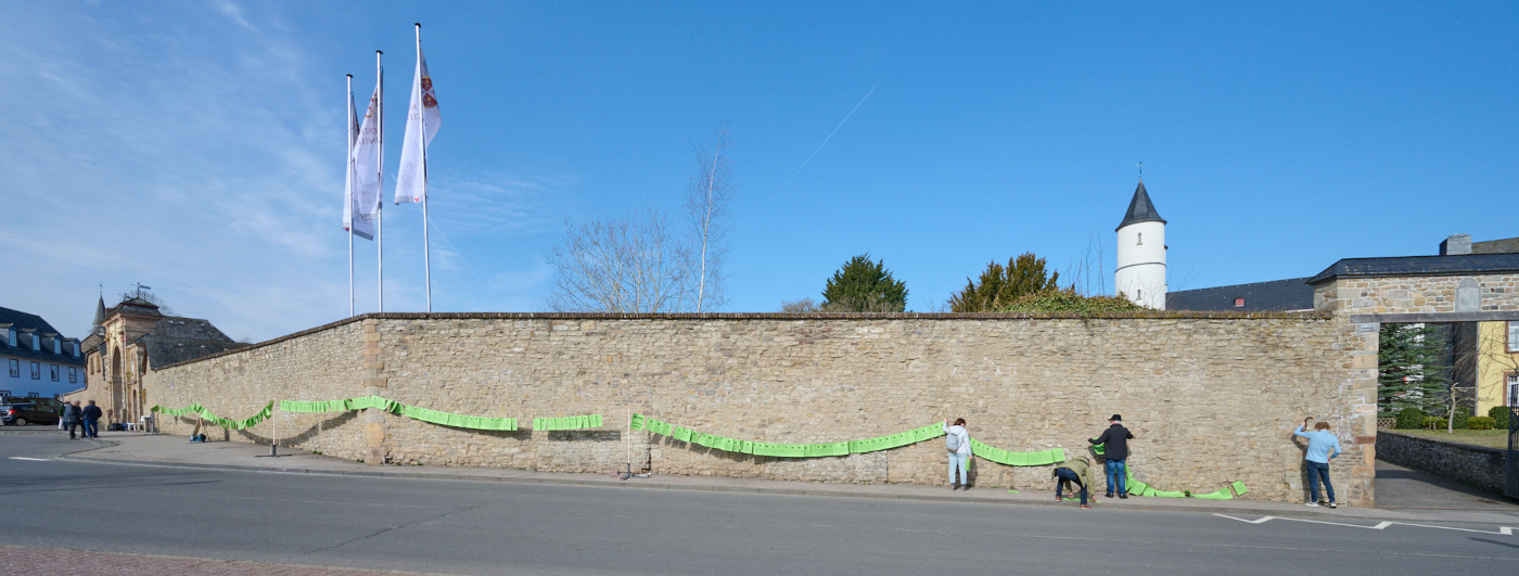 Aktive des Vereins "Eckiger Tisch" stellen die 90 Meter lange Wäscheleine mit den Unterschriften der Petition vor der Mauer des Klosters Steinfeld auf. Dort fand vom 10. bis zum 13. März die Frühjahrs-Vollversammlung der DBK statt. Foto: Helge Articus / Eckiger Tisch e.V.