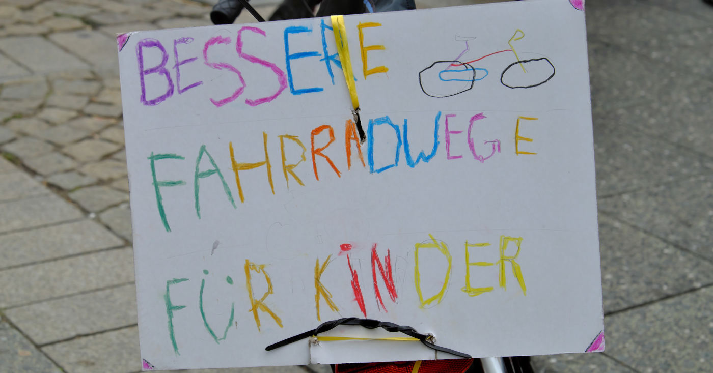 Ein selbstgemaltes Schild auf dem steht: "Bessere Fahrradwege für Kinder!