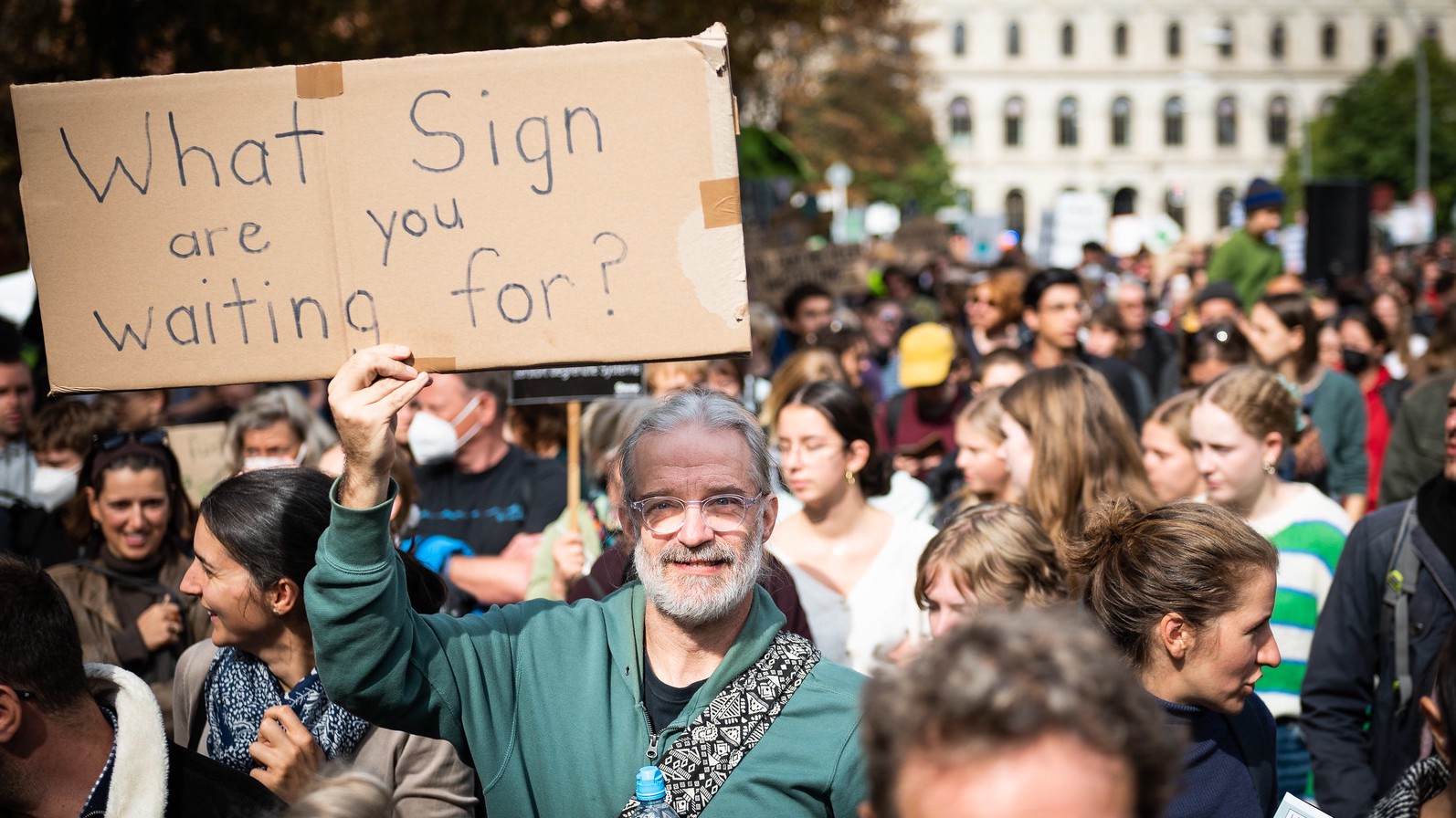 Ein Mann appelliert mit einem selbstgeschriebenen Schild auf einer Demonstration an die Regierung: "Worauf wartet ihr noch?"