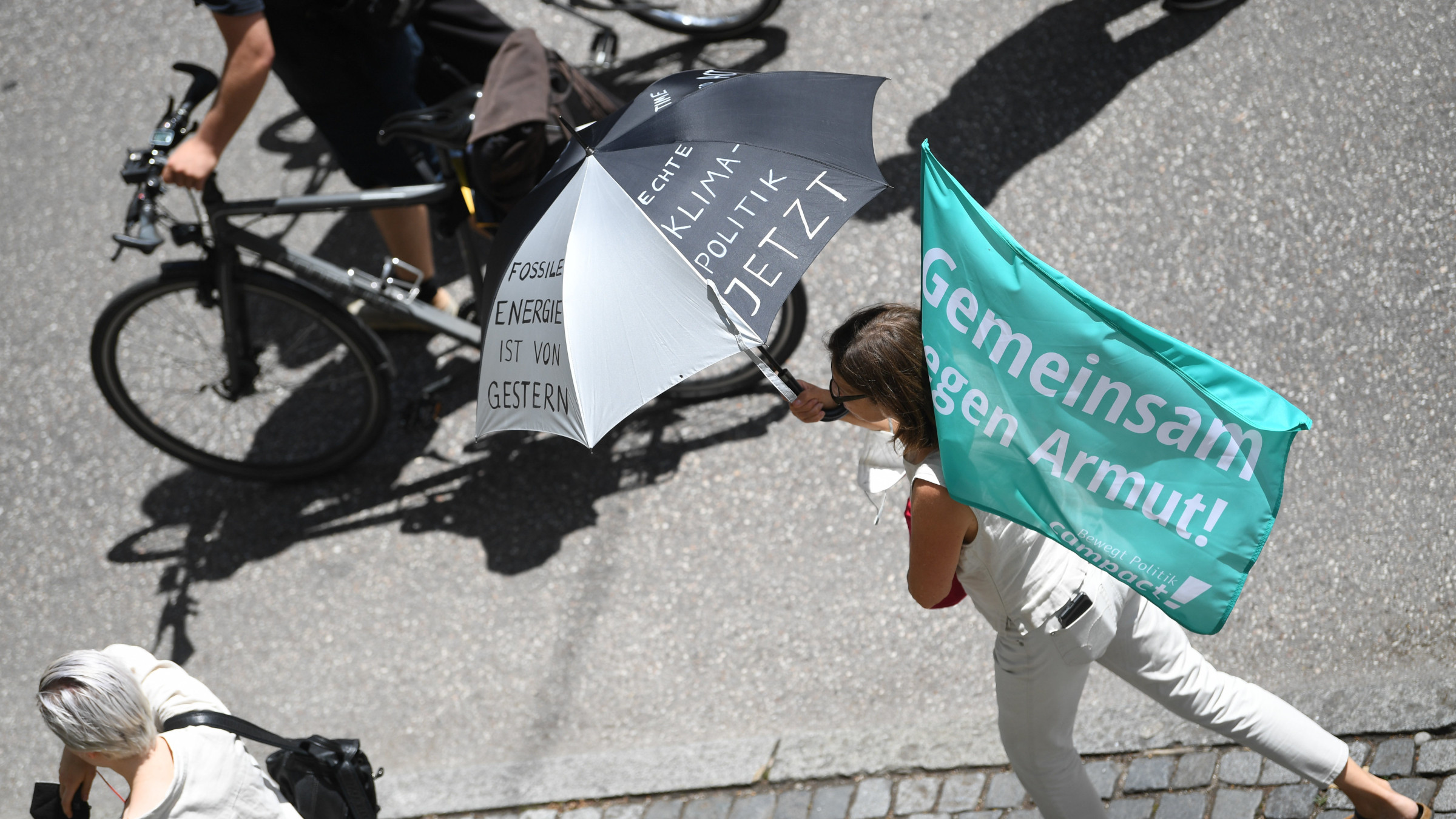 Eine Person bei der G7-Demo 2023. Sie hält eine Flagge von Campact in der Hand auf der steht: Gemeinsam gegen Armut.