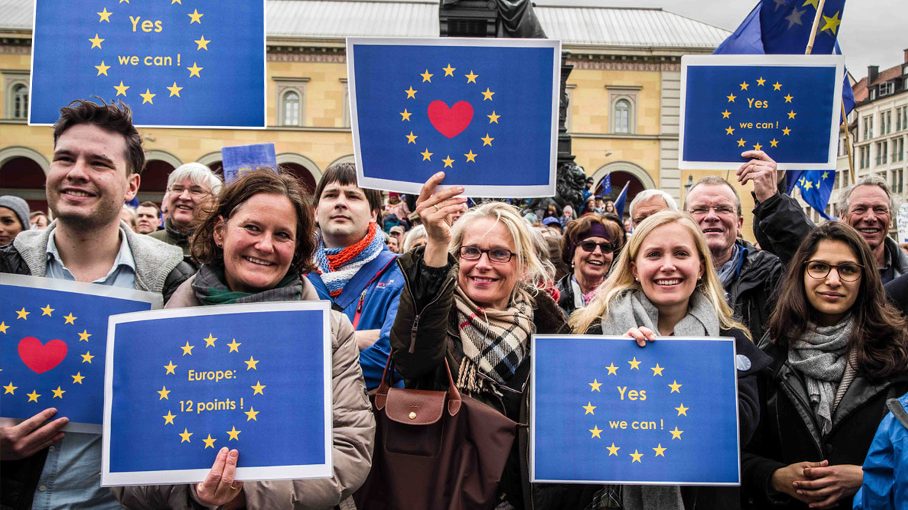 Fröhliche Menschen halten EU-Flaggen hoch