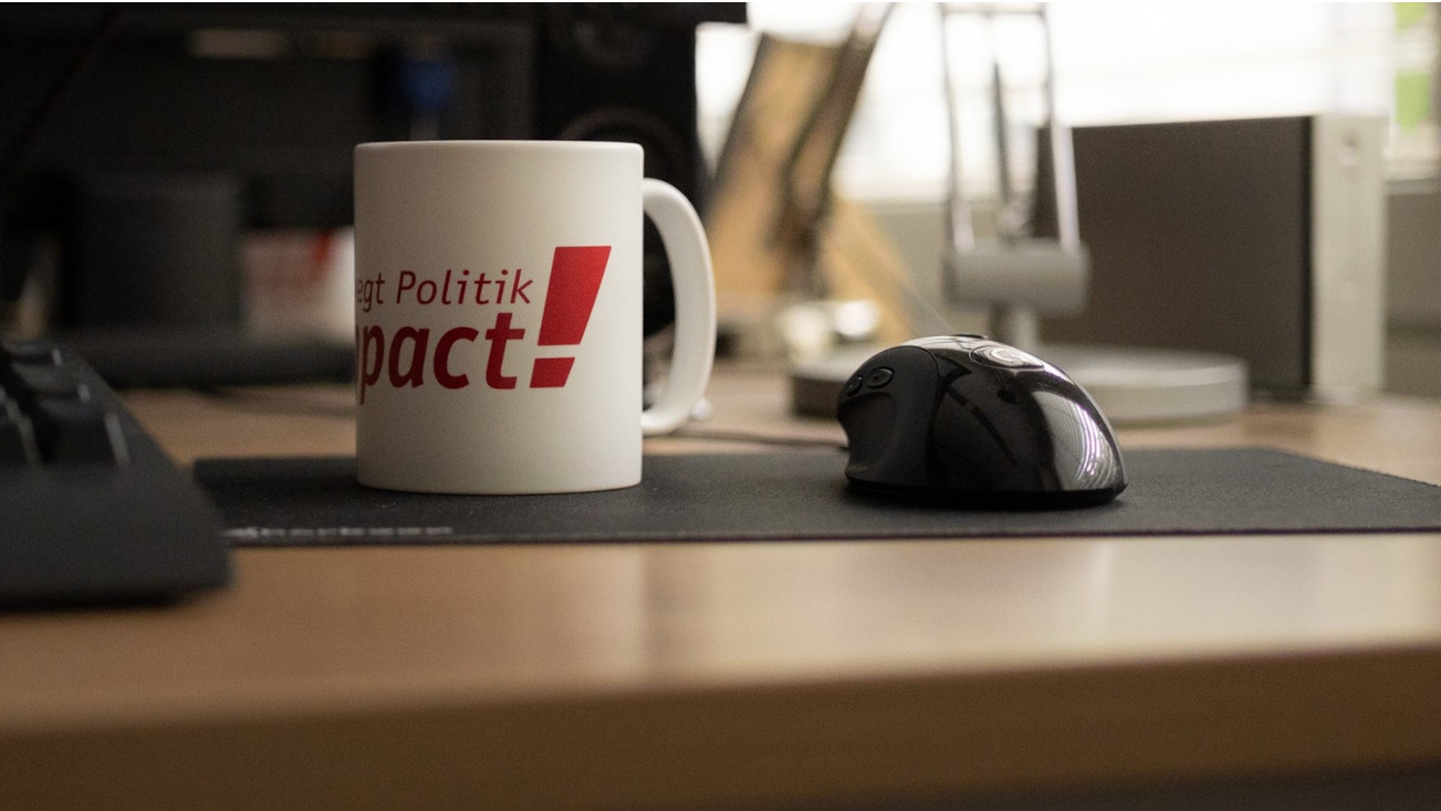 Eine Kaffeetasse von Campact auf einem Schreibtisch.
