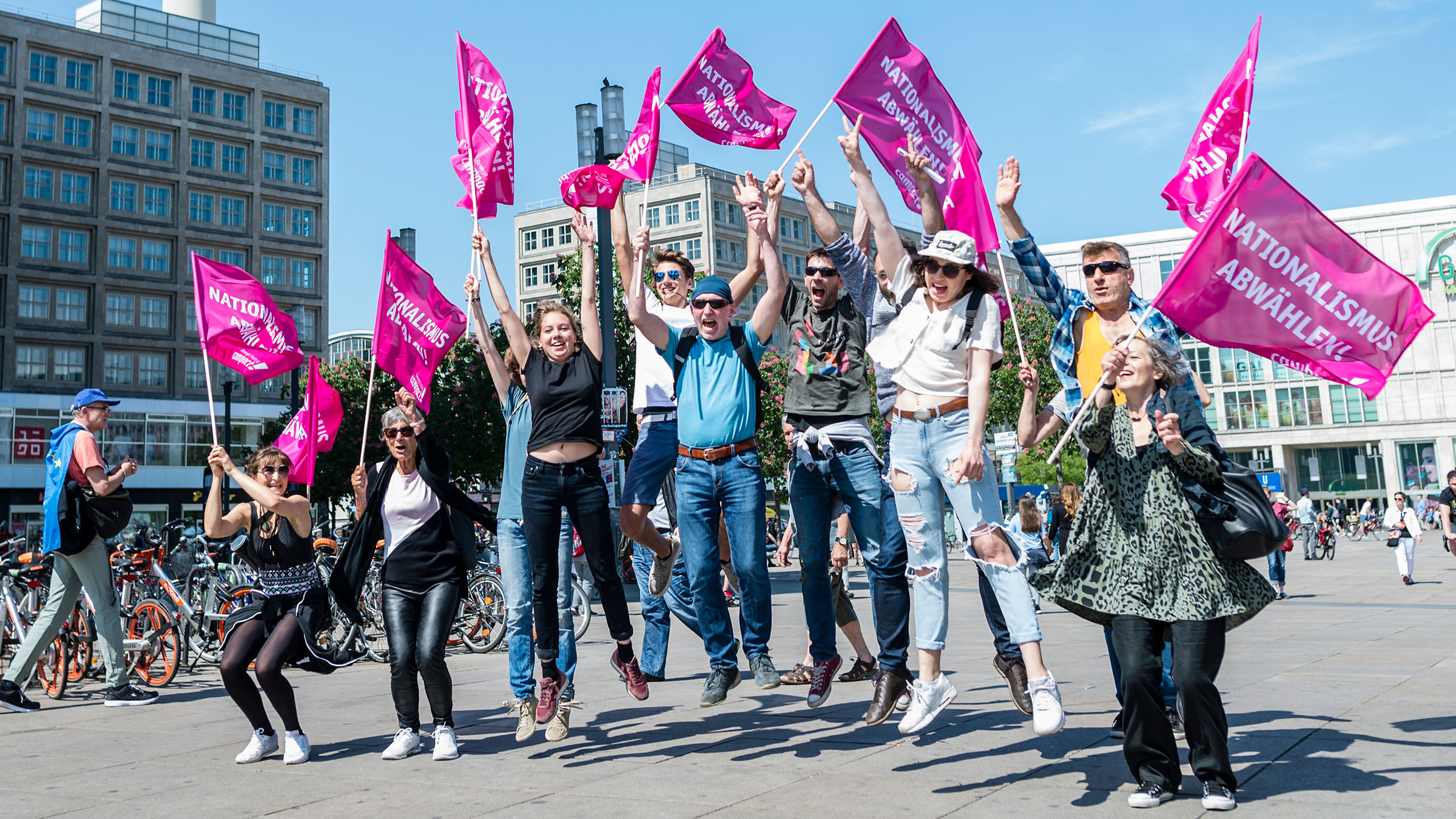 Eine Gruppe von Menschen mit "Nationalismus abwählen"-Flaggen in der Hand springen bei einer Demo vor der Europawahl 2019 gemeinsam in die Luft.