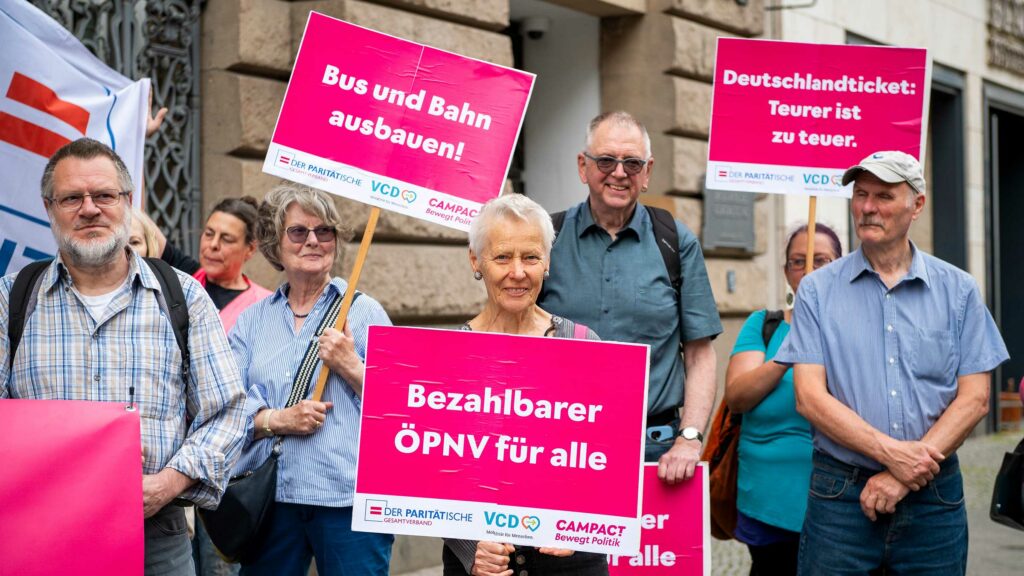 Mehrere Menschen protestieren vor dem der Bayerischen Landesvertretung in Berlin für die Zukunft des Deutschlandtickets.