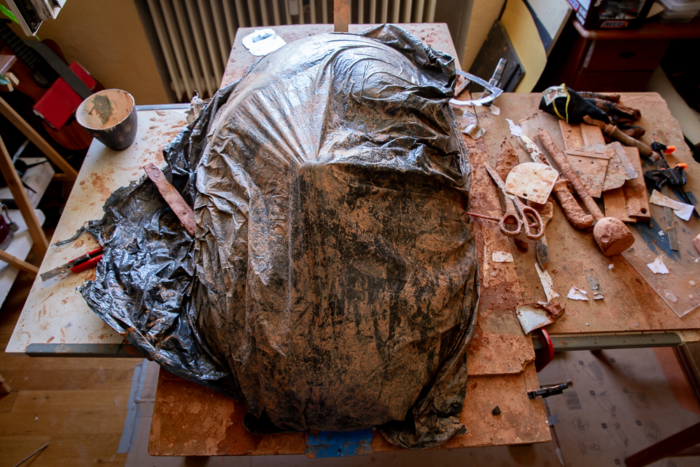 Die schwarze Plastikplane hält den Ton feucht, der das Grundgerüst für die Maske bildet.