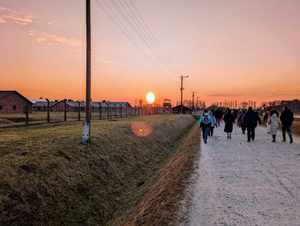 Eine geführte Besuchergruppe läuft über die Lagerstraße des Konzentrationslagers Auschwitz, März 2026.