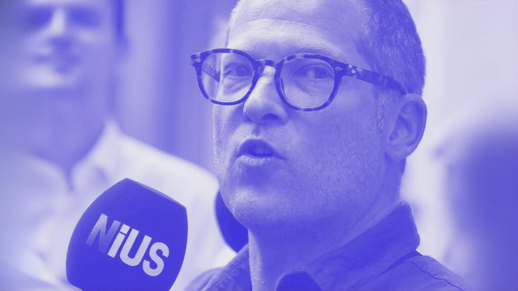 Nius-Chef Julian Reichelt bei einer Demonstration mit einem Mikrofon mit Nius-Logo