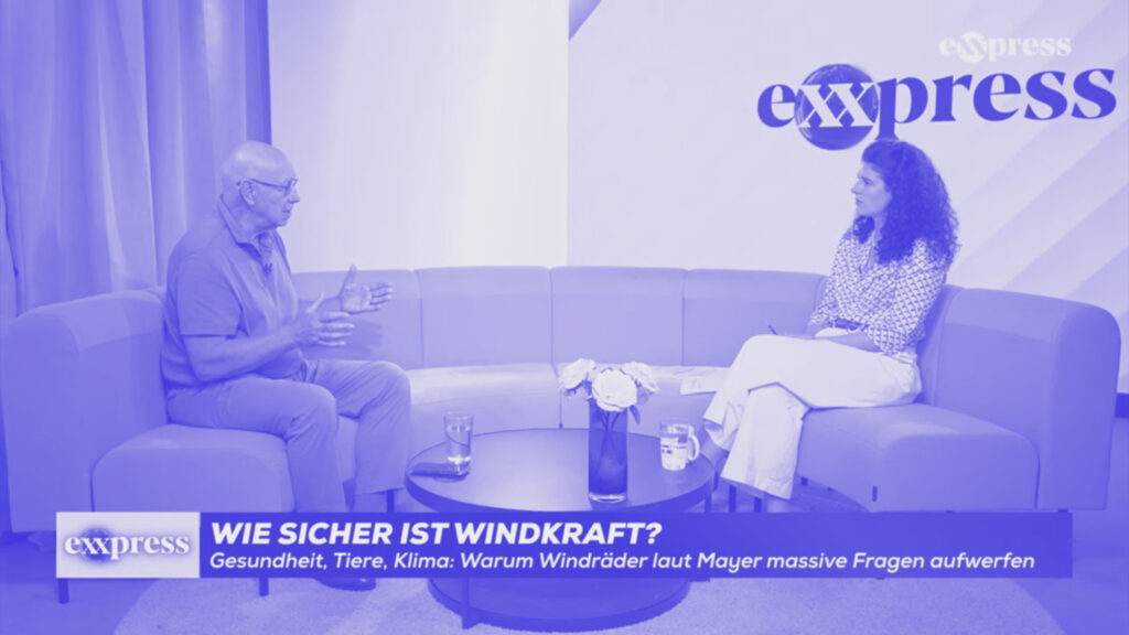 Peter F. Mayer im Interview beim Exxpress. Mayer und die Moderatorin sitzen auf einem Sofa, eingeblendet ist die Frage: "Wie sicher ist Windkraft?"